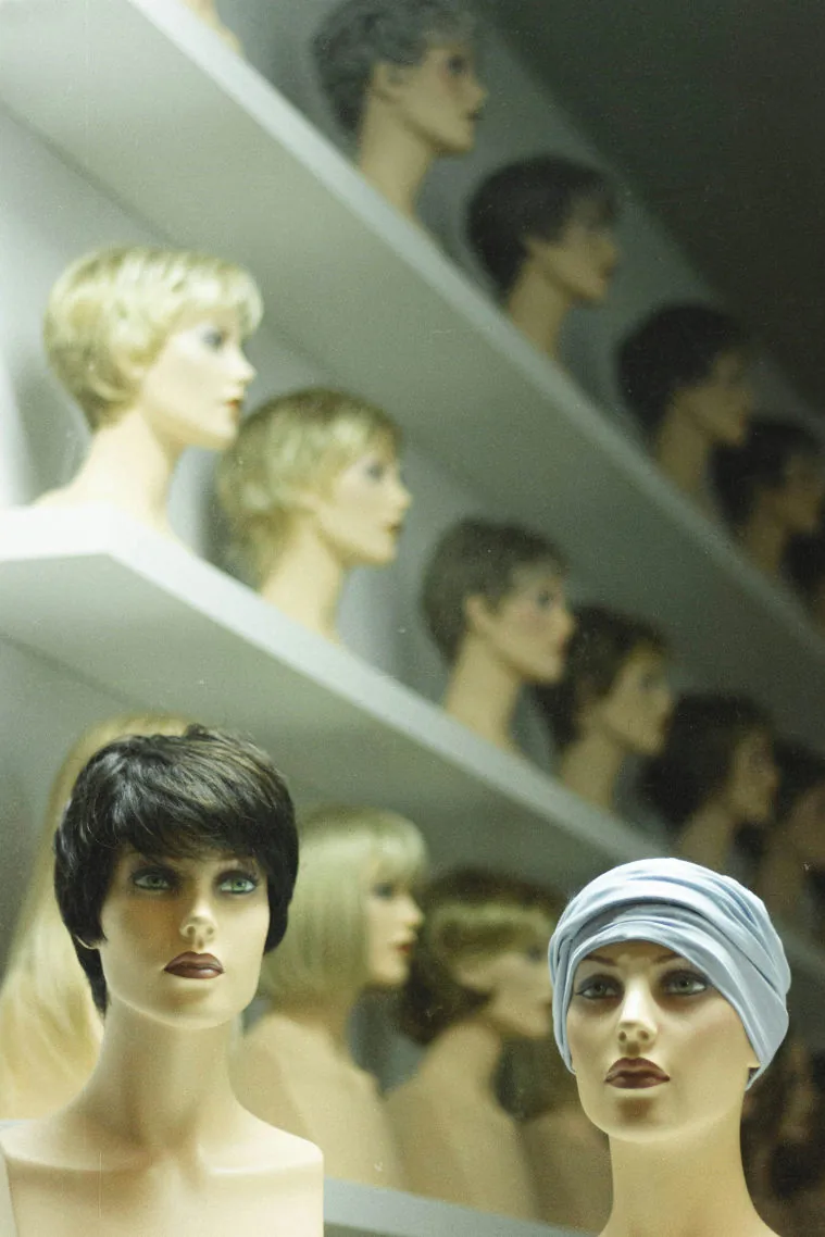 Têtes de mannequins portant des perruques, alignées sur des étagères